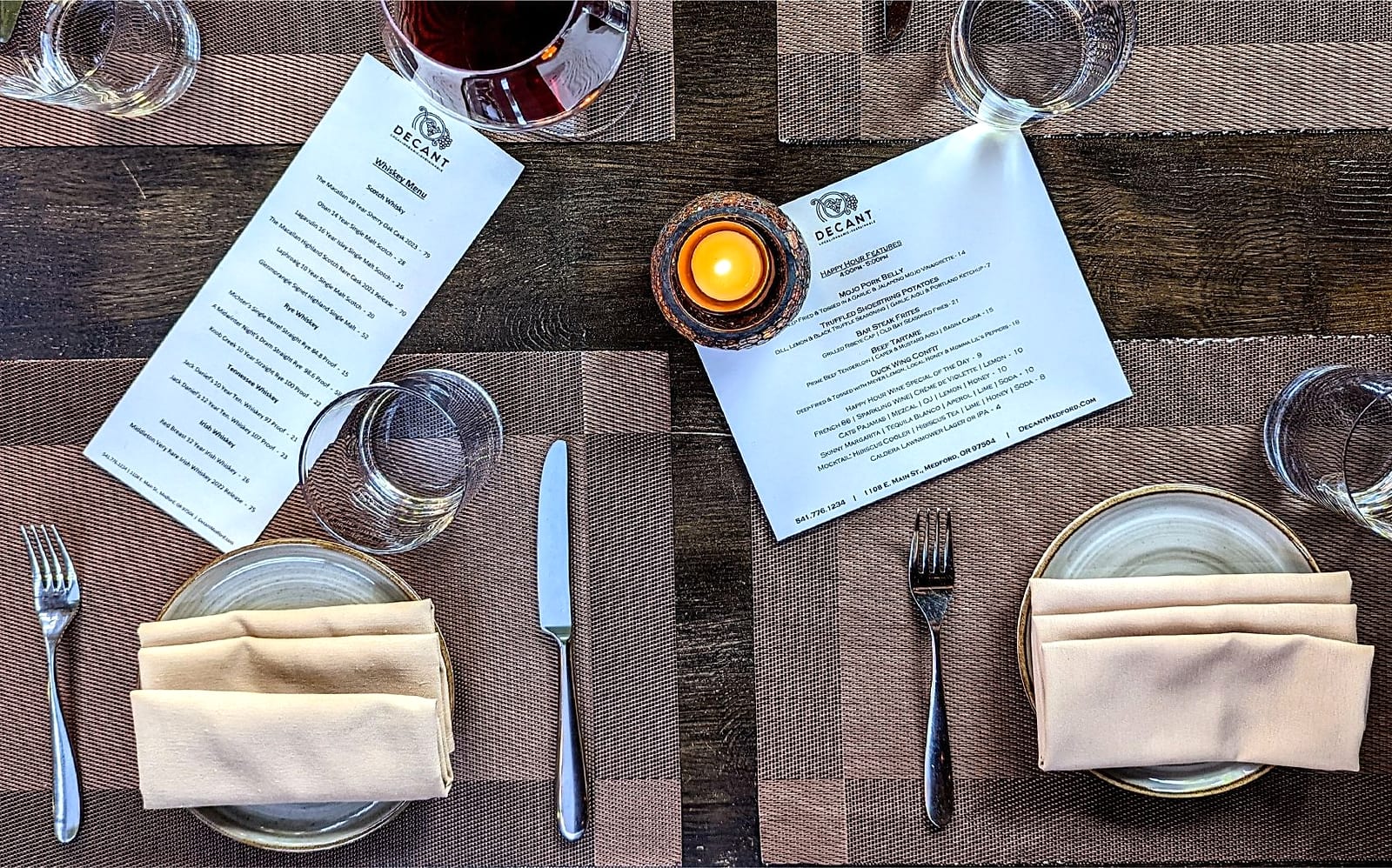 Overhead view of a set table with menus, a candle, glassware and folded napkins